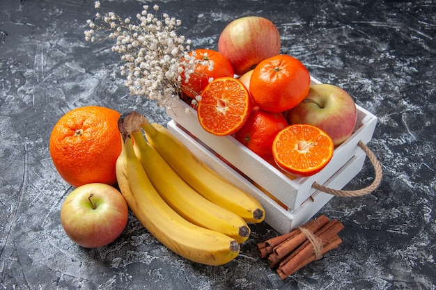Vista superior de frutas frescas en caja palitos de canela sobre fondo gris