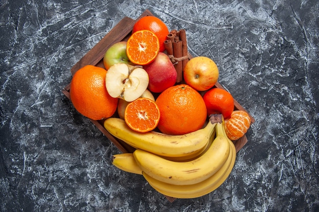 Foto gratuita vista superior de frutas frescas cortadas y palitos de canela en bandeja de madera en la mesa