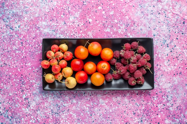 Vista superior de frutas frescas dentro de forma negra sobre superficie rosa