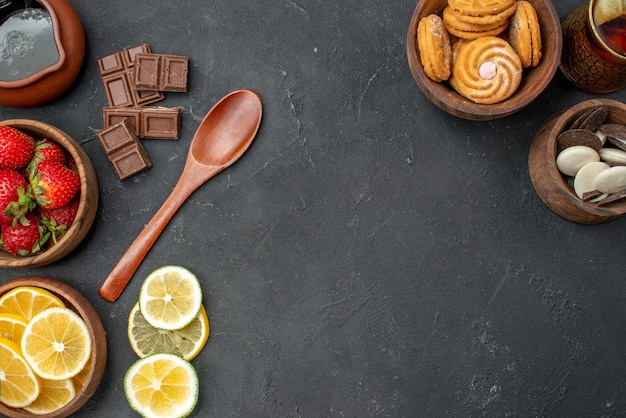 Vista superior de frutas frescas fresas y limones con galletas en superficie gris