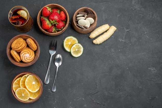 Vista superior de frutas frescas fresas y limones con galletas en superficie gris