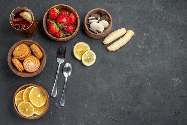 Vista superior de frutas frescas fresas y limones con galletas en superficie gris