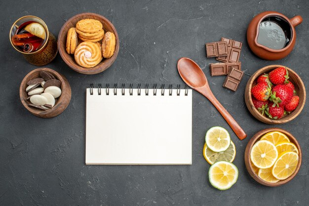 Vista superior de frutas frescas fresas y limones con galletas en superficie gris