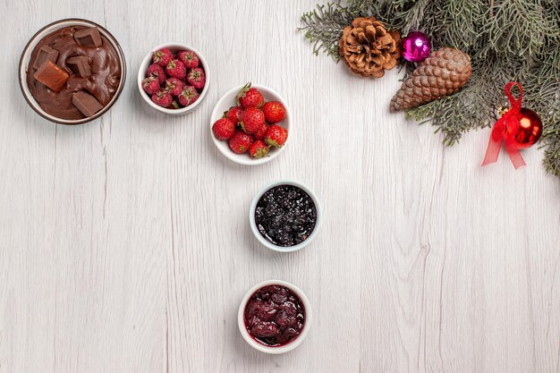 Vista superior de frutas frescas con gelatinas y postre de chocolate en mesa blanca