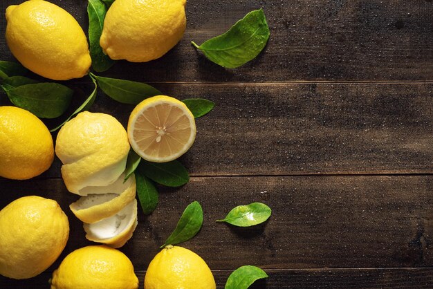 Vista superior de frutas frescas de limón amarillo con hojas sobre fondo de mesa de madera húmeda con espacio de copia Fotografía de bodegones