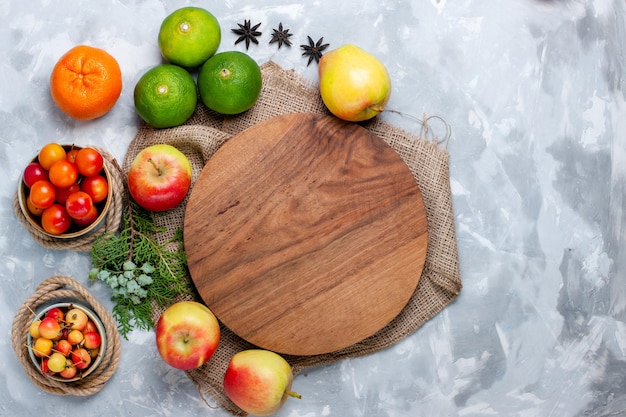 Vista superior frutas frescas manzanas ciruelas y mandarinas en escritorio blanco claro