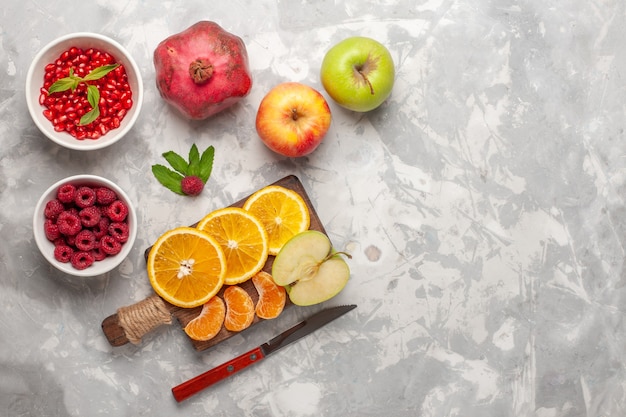 Vista superior de frutas frescas naranjas, frambuesas y granadas en superficie blanca fruta fresca jugo de vitamina suave exótica tropical