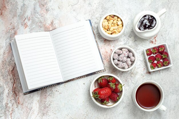 Vista superior de frutas frescas con nueces y una taza de té sobre fondo blanco, nueces, frutas, bayas, té, dulces