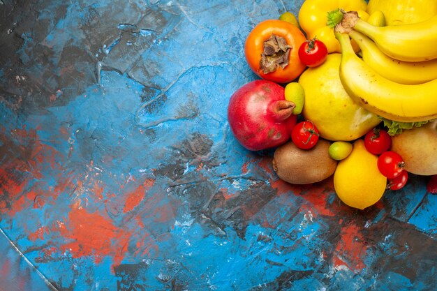 Vista superior de frutas frescas, plátanos, uvas y otras frutas en el escritorio azul dieta foto suave salud color maduro sabroso