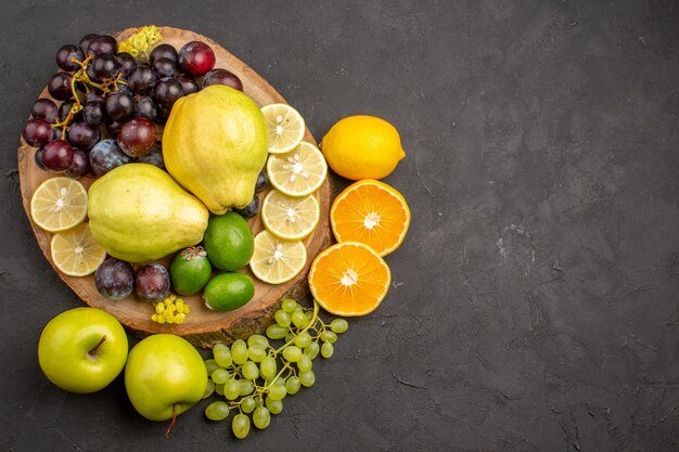 Vista superior frutas frescas uvas rodajas de limón ciruelas y membrillos en la superficie oscura frutas frescas maduras salud vitamina árbol