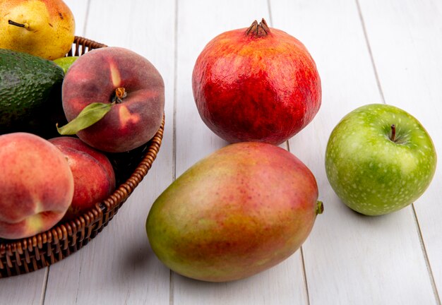 Vista superior de frutas jugosas como la pera melocotón en un cubo con mango de manzana aislado en una superficie blanca