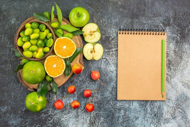 Vista superior de frutas lejanas las apetitosas bayas frutas en la pizarra cuaderno de lápiz