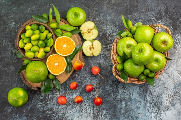 Vista superior de frutas lejanas las apetitosas cerezas mandarinas en el tablero cesta de manzanas