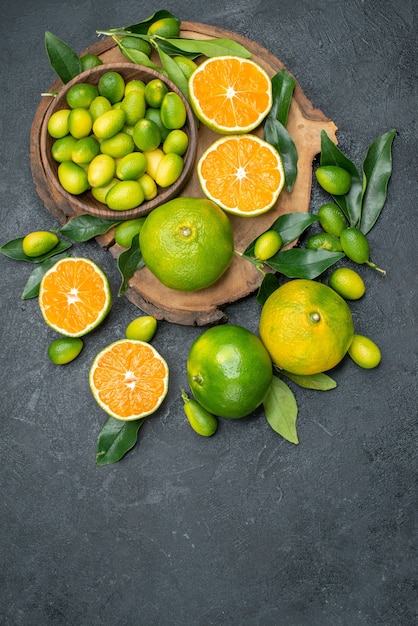 Vista superior de frutas lejanas el tablero de diferentes frutas cítricas en la mesa oscura