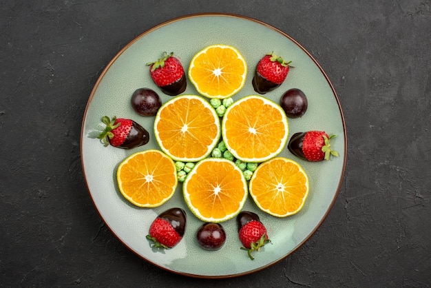 Vista superior de frutas y naranja picada de chocolate con fresas cubiertas de chocolate y caramelos verdes
