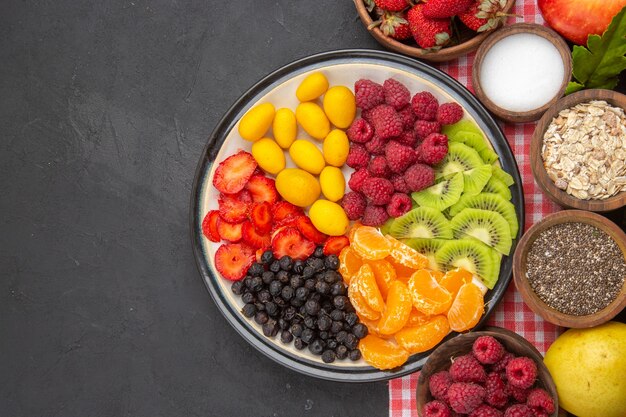 Vista superior de frutas en rodajas con frutas frescas sobre un fondo oscuro