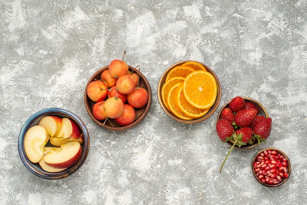 Vista superior de frutas en rodajas, manzanas y naranjas con bayas sobre fondo claro fruta fresca vitamina suave salud