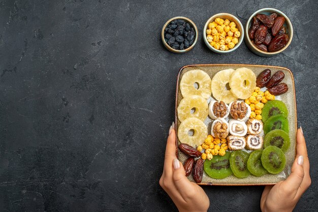 Vista superior de frutas secas en rodajas, anillos de piña y kiwis en un escritorio gris fruta seca pasas vitamina dulce salud agria