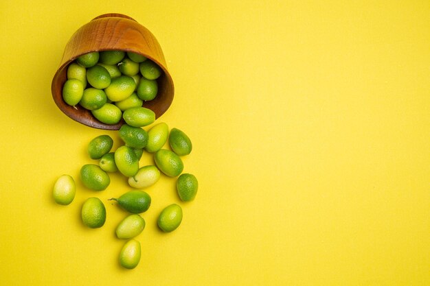 Vista superior de las frutas en un tazón de fuente de las apetitosas frutas verdes en el tabl