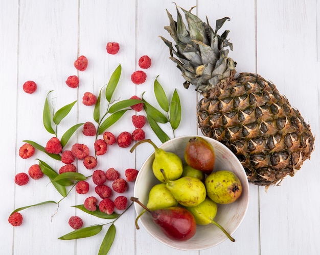 Foto gratuita vista superior de frutas en un tazón con hojas sobre superficie de madera