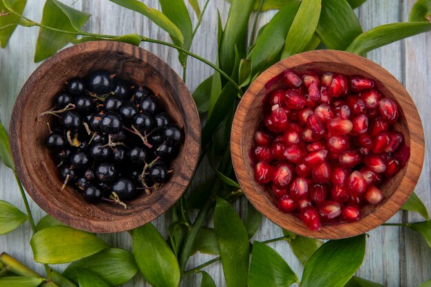 Foto gratuita vista superior de frutas en tazones sobre superficie de madera decorada con hojas