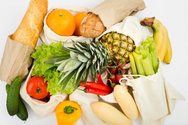 Vista superior de frutas y verduras en bolsas reutilizables con pan