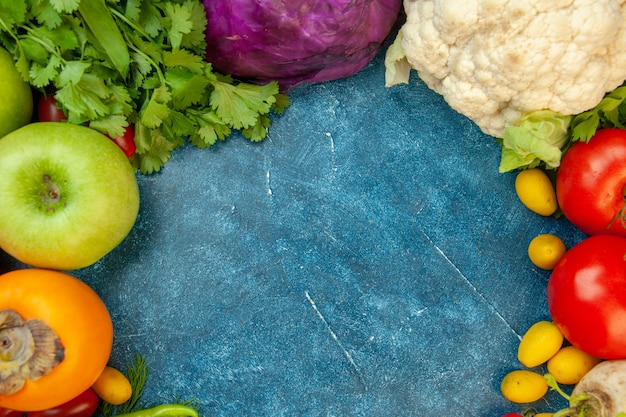 Vista superior de frutas y verduras, tomate, cilantro, manzana, caqui, col lombarda, coliflor en el cuadro azul