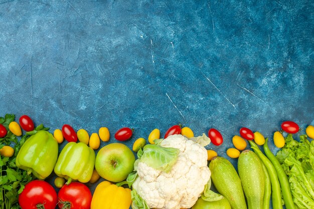 Vista superior frutas y verduras tomates cherry tomates cumcuat coliflor zacchini en mesa azul