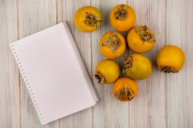 Vista superior de frutos de caqui amarillo aislado en una mesa de madera gris con espacio de copia