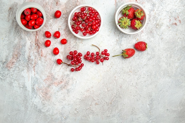 Vista superior de frutos rojos con bayas en una mesa blanca baya de frutos rojos frescos
