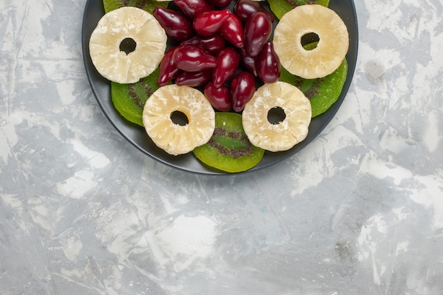 Foto gratuita vista superior de frutos secos anillos de piña y rodajas de kiwi sobre fondo blanco frutos secos azúcar dulce agrio