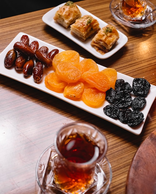 Vista superior de frutos secos con baklava turco y un vaso de armudu de té