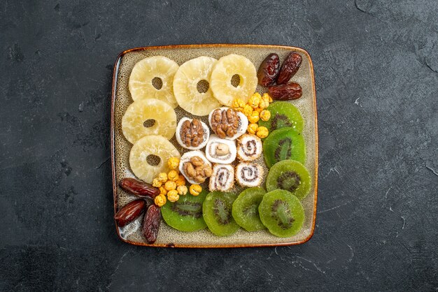 Vista superior de frutos secos en rodajas anillos de piña y kiwis sobre un fondo gris frutos secos pasas vitamina agridulce salud