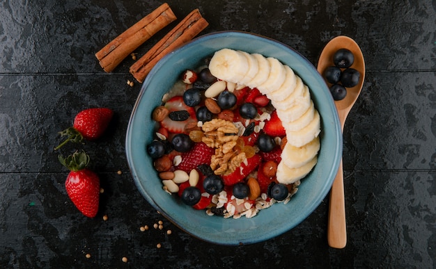 Vista superior de gachas de avena con cuchara de madera y palitos de canela