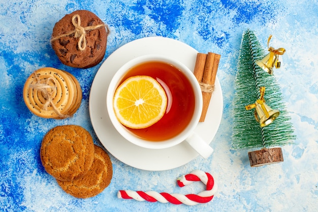 Vista superior de las galletas atadas con una cuerda taza de té pequeño árbol de Navidad en la mesa azul