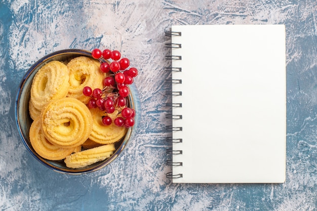 Vista superior de galletas de azúcar con frutos rojos sobre superficie azul claro