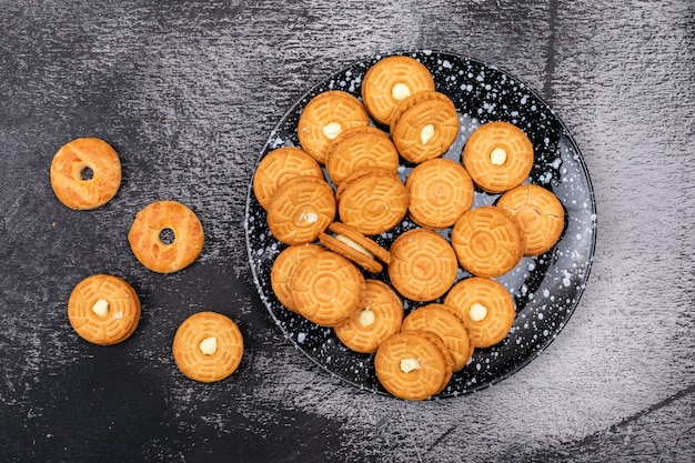 Vista superior de galletas de azúcar en placa sobre superficie oscura