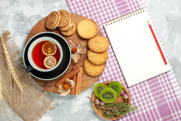 Vista superior de las galletas de azúcar con una taza de té y un bloc de notas en una pared blanca pastel de galletas galletas pastel