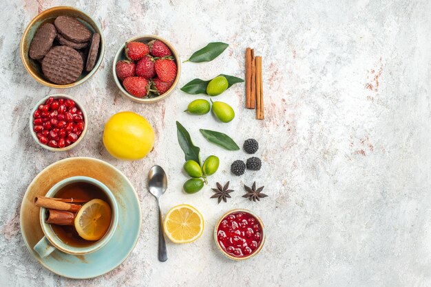 Vista superior galletas y bayas apetitosas galletas fresas cuchara una taza de té frutas cítricas canela sobre la mesa