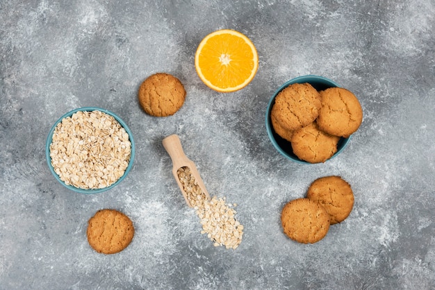 Foto gratuita vista superior de galletas caseras sobre tabla de madera y avena con naranjas.