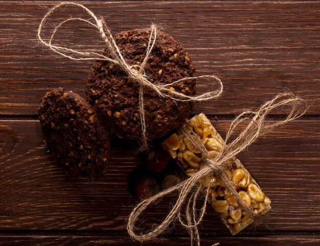 Vista superior de galletas de chispas de chocolate con cereales, nueces y cacao atados con una cuerda en madera