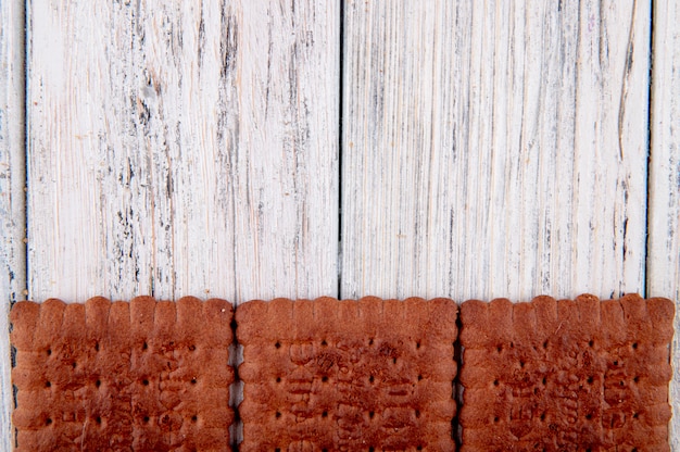 Foto gratuita vista superior galletas de chocolate en la parte inferior con espacio de copia sobre fondo blanco de madera