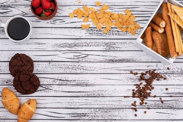 Vista superior de galletas y copos de maíz con galletas, café y copia espacio sobre fondo blanco de madera horizontal