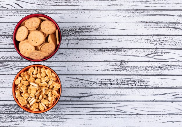 Vista superior de galletas en cuencos con espacio de copia a la derecha en horizontal de madera blanca