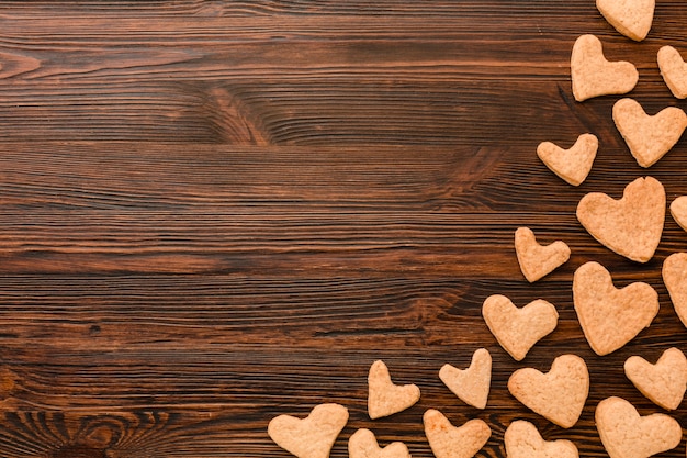 Vista superior de las galletas del día de san valentín en forma de corazón sobre fondo de madera