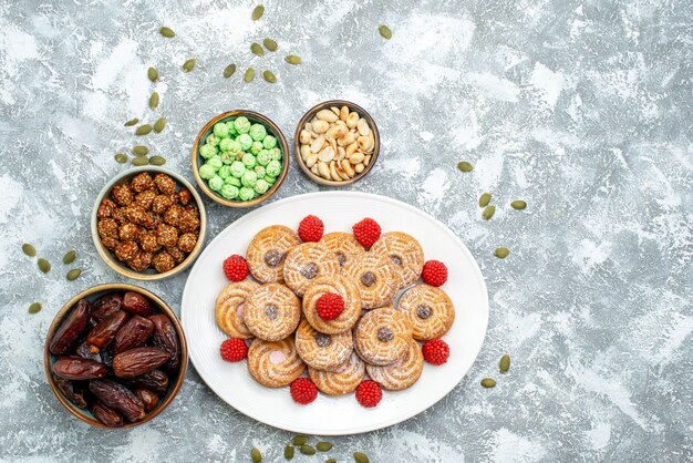 Vista superior de las galletas dulces con caramelos y confituras sobre fondo blanco, galletas de azúcar, galletas, té, pastel dulce