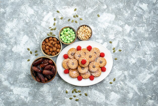 Vista superior de las galletas dulces con caramelos y confituras sobre fondo blanco, galletas de azúcar, galletas, té, pastel dulce