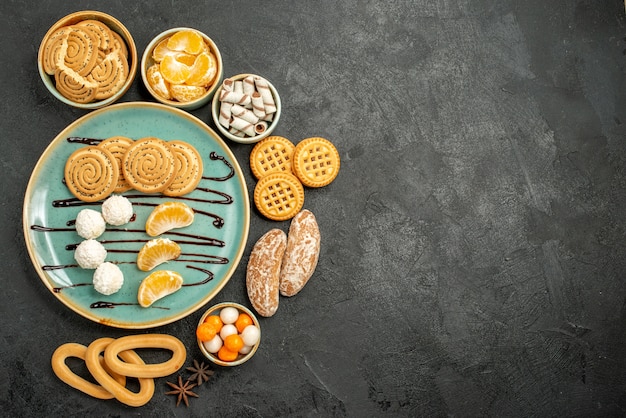 Vista superior de galletas dulces con caramelos y galletas sobre fondo gris