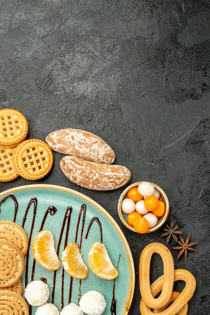 Vista superior de galletas dulces con caramelos y galletas sobre fondo gris