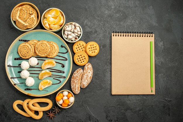 Vista superior de galletas dulces con caramelos y galletas sobre fondo gris